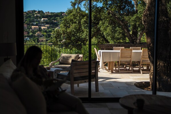Un balcone con vista su un pendio collinare, arredi in legno e una porta vetrata.