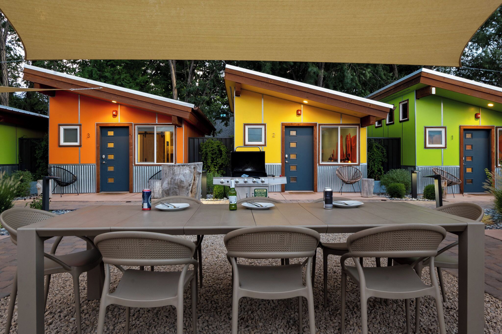 A patio area with a table and chairs, a barbecue grill, and colorful houses in the background.
