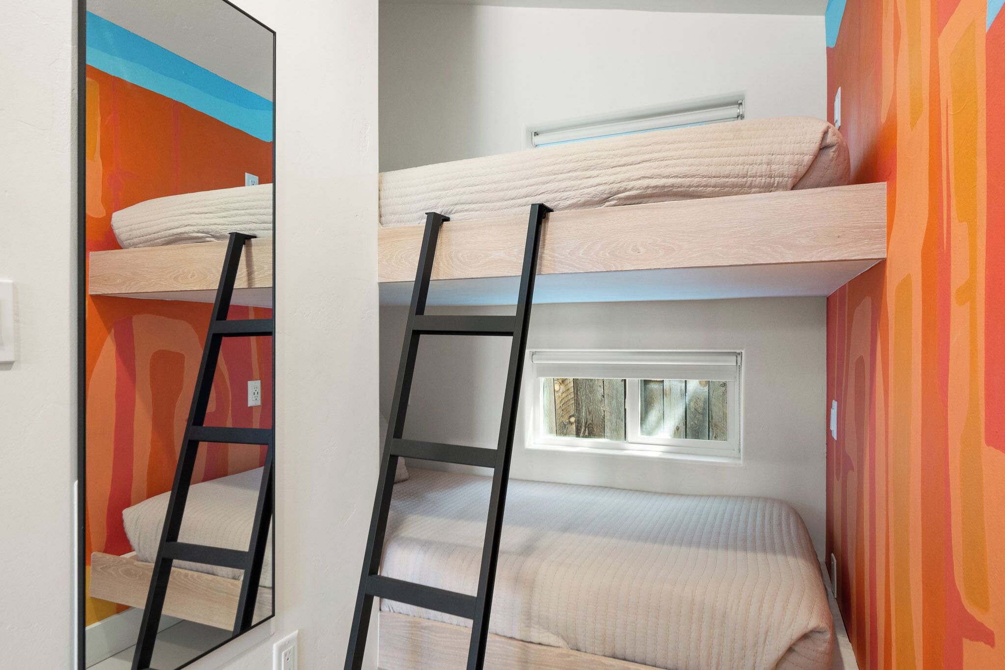 A room with bunk beds, a ladder, and a window.