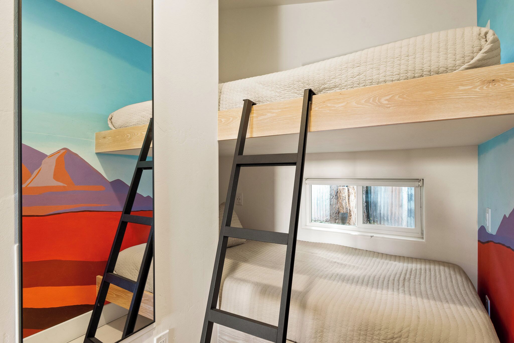 A bunk bed with a ladder, a window, and a mural on the wall.