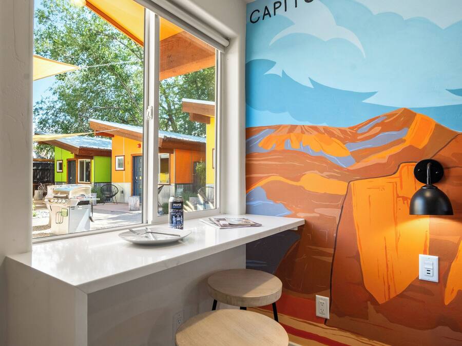 A kitchen with a window, a mural, and a countertop with a plate and a can.