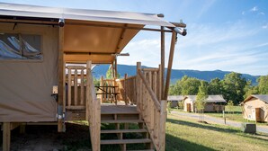 A wooden deck leading to a tent with a view of mountains.