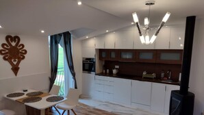 A modern kitchen with white cabinets, a built-in oven, and a black stove. - Lovely Mountain Apartment Zakopane 14km (Suchá Hora)