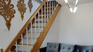 A modern living room with a wooden staircase, a blue sectional sofa, and a wooden coffee table. - Lovely Mountain Apartment Zakopane 14km (Suchá Hora)