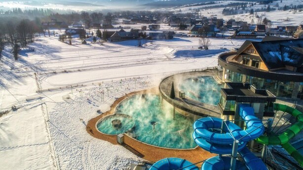 A resort with a hot spring area, a water slide, and a view of snow-covered mountains. - Lovely Mountain Apartment Zakopane 14km (Suchá Hora)