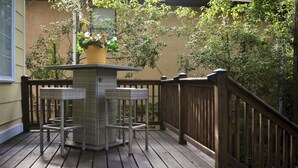 Une terrasse en bois avec une table centrale et deux chaises, entourée d’une balustrade en bois.