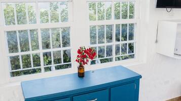 A room with a blue cabinet, a vase with red flowers, and a TV on the wall.