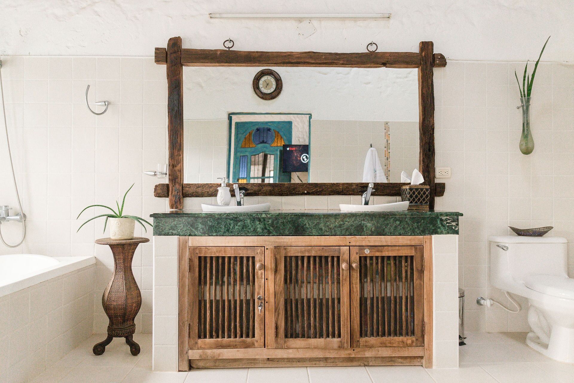 A bathroom with a wooden vanity, a large mirror, and a bathtub.