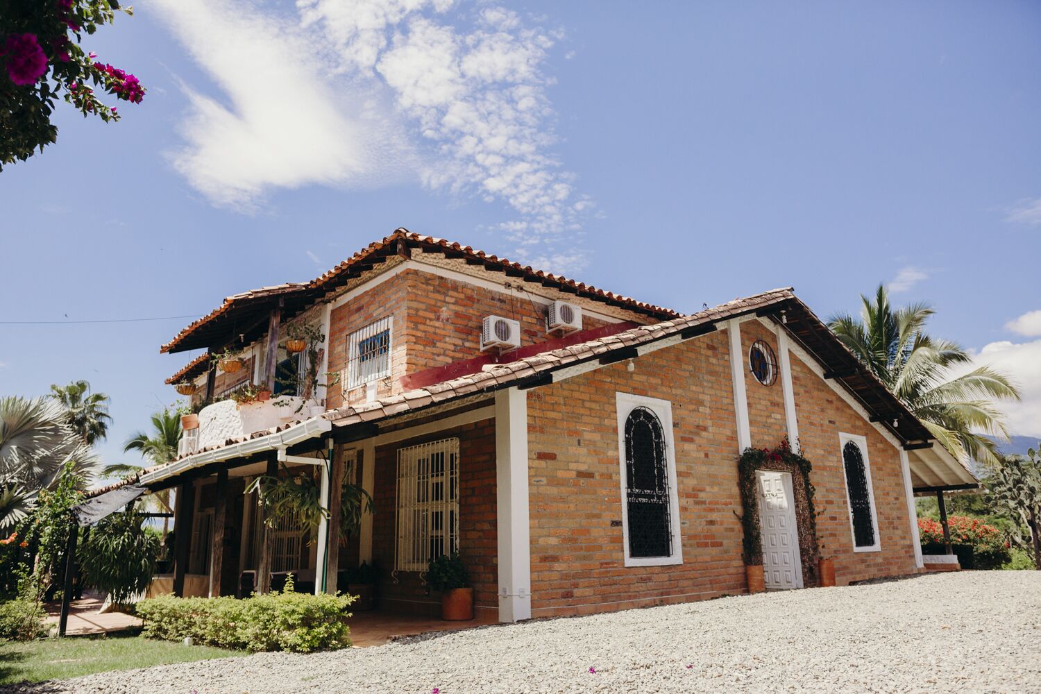 Una casa de dos pisos con fachada de ladrillo, techo de tejas y porche cubierto.