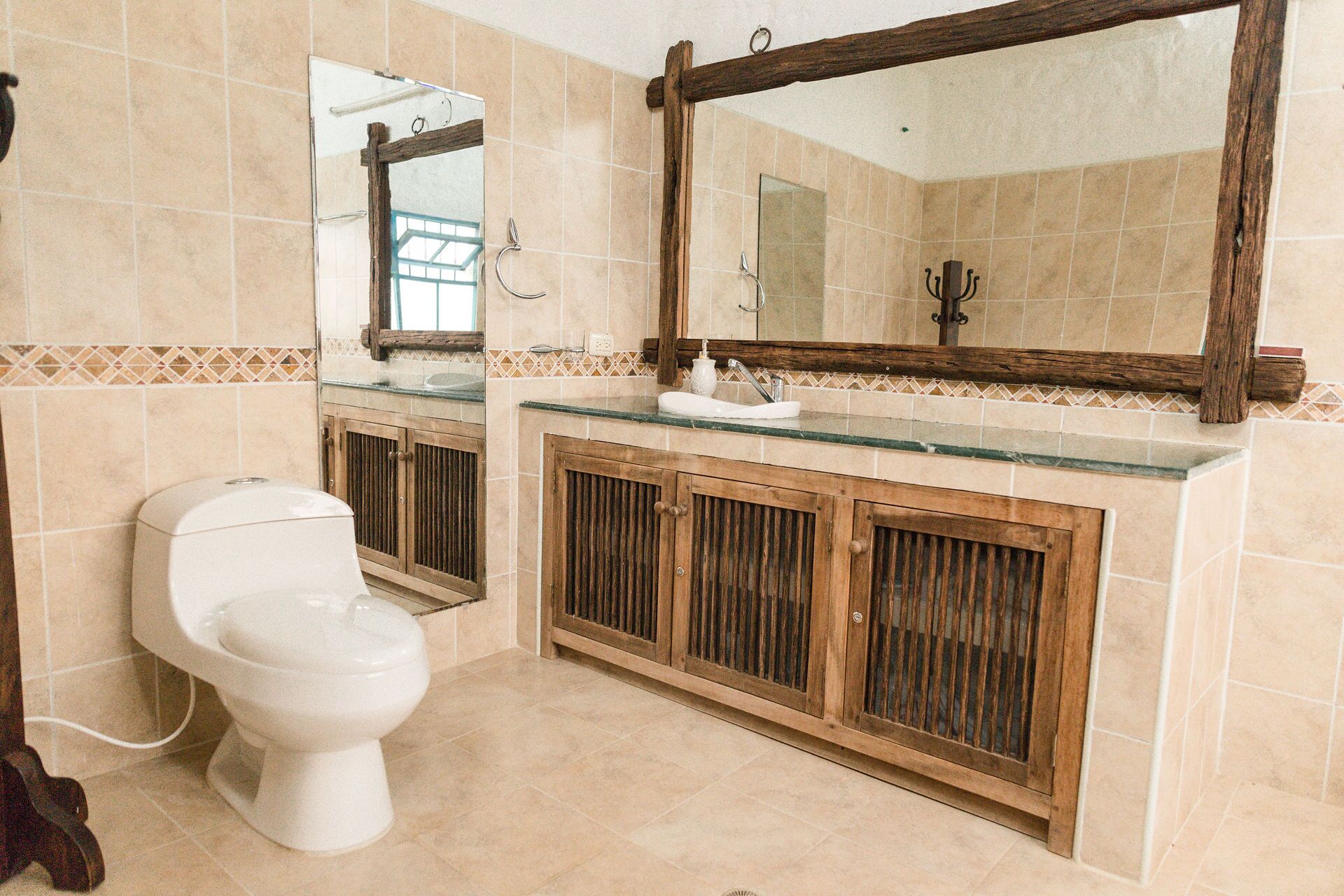A bathroom with a toilet, a sink with a glass countertop, and wooden cabinets.