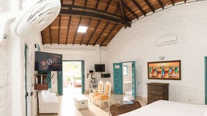 A room with a bed, a television, a fan, a painting, and a door leading to another room. - HOTEL KALMA  (Santa Fe de Antioquia)