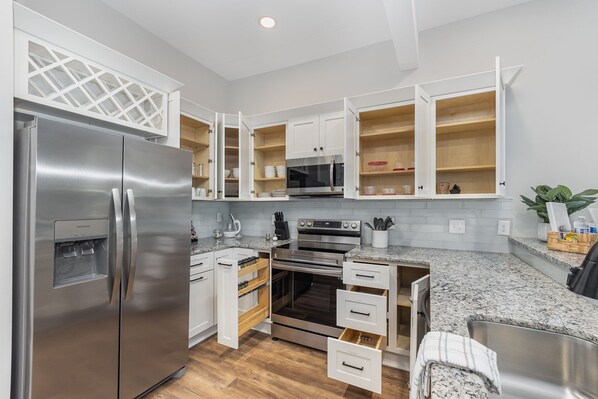 A modern kitchen with white cabinetry, stainless steel appliances, and a granite countertop.