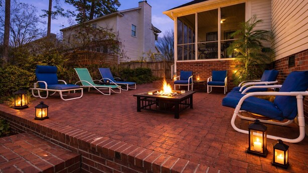 Eine Terrasse mit Sitzgelegenheiten, einem Feuerkorb und Laternen.