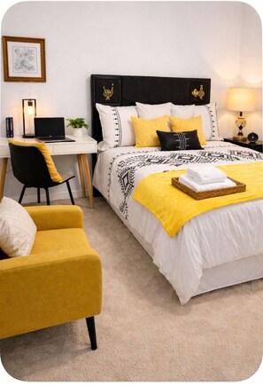 Une chambre d’hôtel avec un lit, un bureau avec un ordinateur portable, une chaise, une lampe et un tableau encadré au mur.