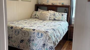 A bedroom with a bed, wooden headboard, and a nightstand.