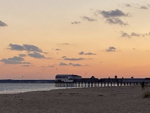 A beach with a pier extending into the water, featuring a building with multiple levels. - Oceanview! Cozy Condo with Kitchen, Living Area, Porch, 2 Reserved Parking Spots (Old Orchard Beach)