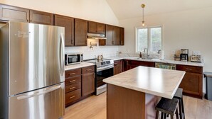Una cocina moderna con electrodomésticos de acero inoxidable, armarios de madera y encimera de mármol.