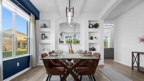 Een eetruimte met een glazen tafel, bruine stoelen en een kroonluchter.