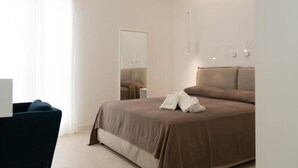 A modern bedroom with a large bed, a bedside table, a chair, and a mirror. - Maruzza Home 201 (Favignana)