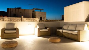 A rooftop terrace with wicker furniture and a large white wall. - Maruzza Home 201 (Favignana)