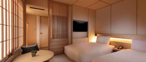 A hotel room with two beds, a TV, a bedside table with a lamp, a small table with a plant, and a sliding door.