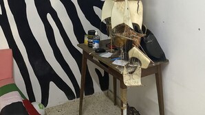 Una habitación con una pared a rayas de cebra, una mesa de madera con un modelo de barco y una ventana pequeña.