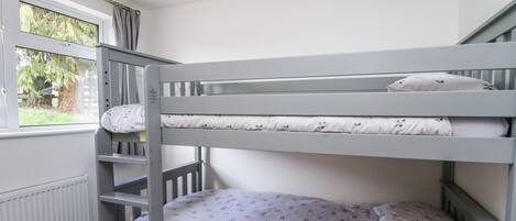 A bunk bed with a window, a radiator, and a book on the lower bunk.