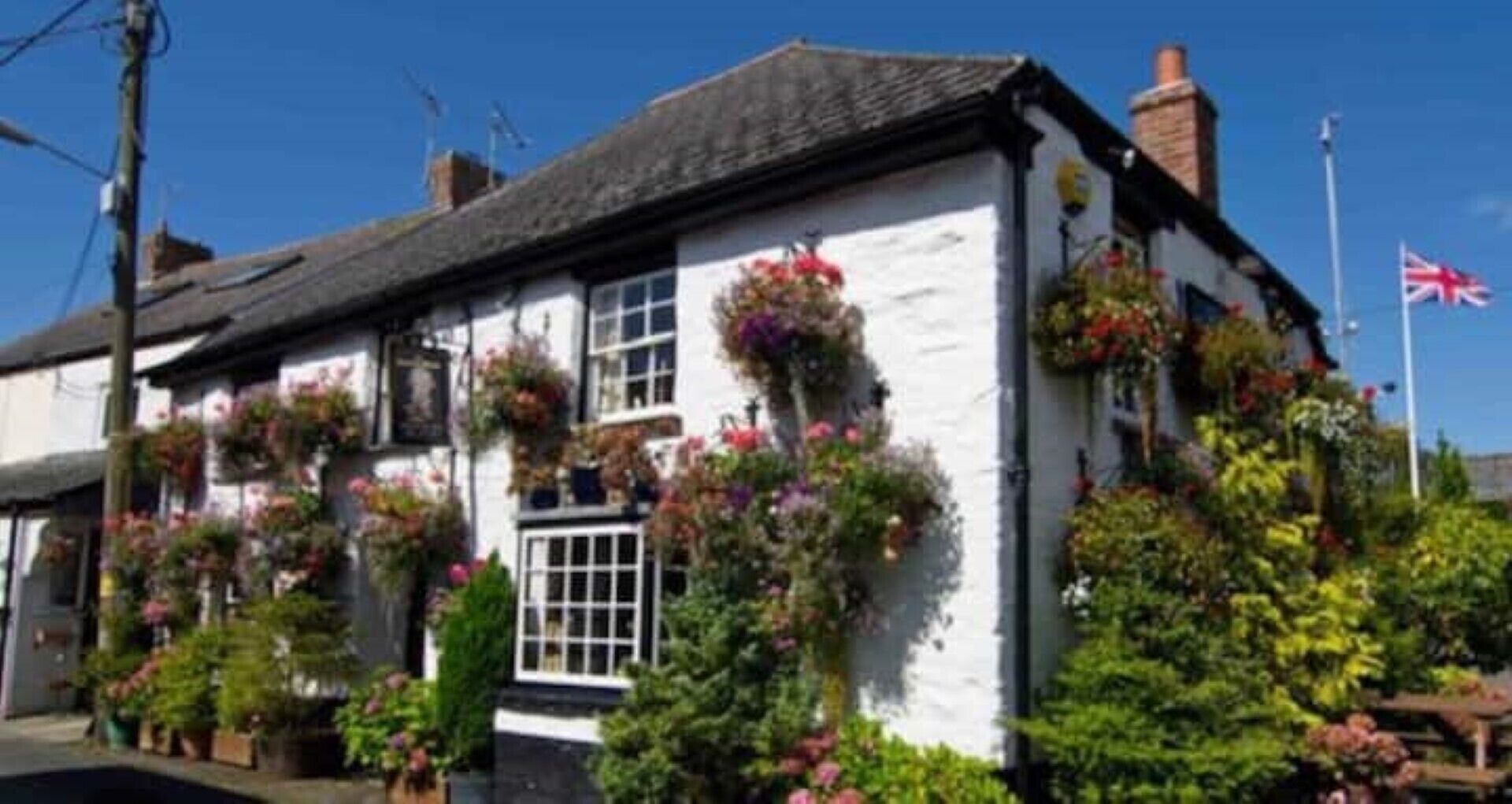 A traditional white building with multiple windows, some with hanging flower baskets.