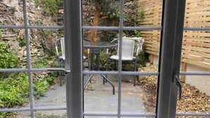 A patio area with a stone wall, a wooden fence, and a table with chairs. - Cute, Cosy, Cornish, Cottage (Wadebridge)