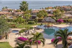 Un resort con una amplia piscina, palmeras y vistas al océano.
