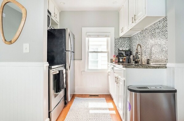 A kitchen with white cabinets, a stainless steel refrigerator, a microwave, and a sink. - Luxe apartment at MIT/Harvard with FREE parking (Cambridge)