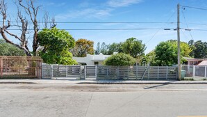 Propriedade murada com um edifício branco, cerca e árvores.