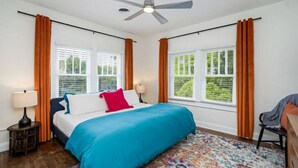 A bedroom with a bed, two bedside lamps, a ceiling fan, and a window with curtains. - Colorful, waterside home (Bradenton)