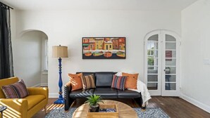 A living room with a black sofa, yellow armchair, and a blue floor lamp. - Colorful, waterside home (Bradenton)