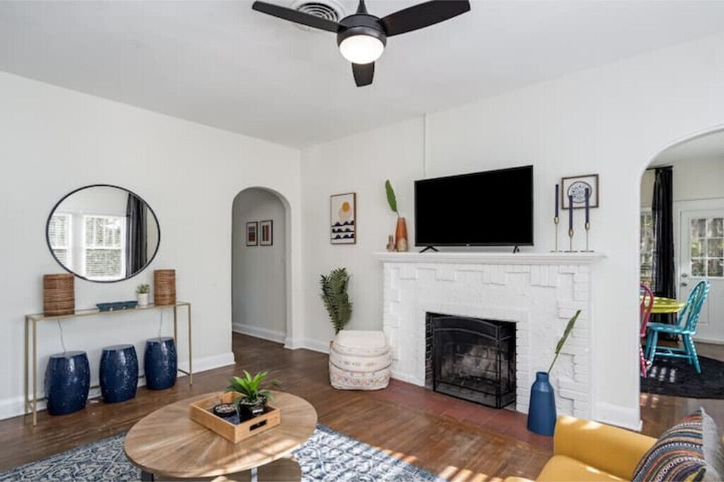 A modern living room with a white fireplace, a round coffee table, and a television mounted above it.