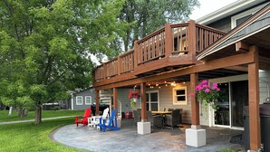 Un patio cubierto con mobiliario exterior, una parrilla y una terraza de madera.