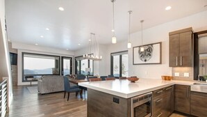 Een moderne keuken met een groot eiland, houten kastjes en hanglampen.