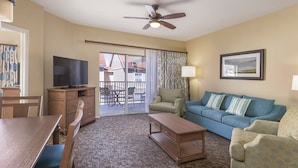 A hotel room with a television, a sofa, a coffee table, a dining table, and a balcony with a view of buildings. - 3BD Deluxe/Branson - w/Pools, BBQ, Game Room, Gym! (Branson)