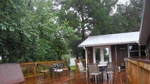 A wooden deck with a hot tub, outdoor seating, and a covered area with a metal roof. - Scallop Hut - Old Homosassa (Homosassa)