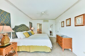 Une chambre à coucher comprenant un lit, des tables de chevet, une commode et un ventilateur de plafond.