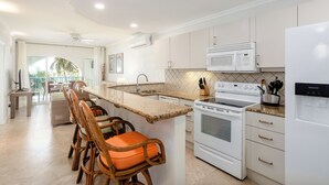A modern kitchen with a central island, white cabinetry, a built-in microwave, and a refrigerator.