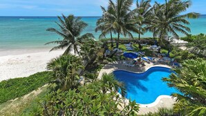 Ein Resort mit Pool, umgeben von Palmen und einem Strand.