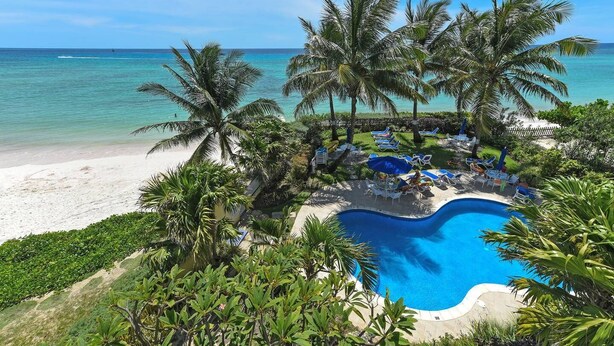 A resort with a pool surrounded by palm trees and a beach. - #302 Oceanview beachfront Maxwell Beach Villas (Christ Church)