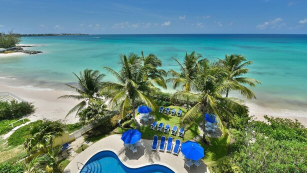 Un resort con piscina, sillas de descanso y vistas al océano.
