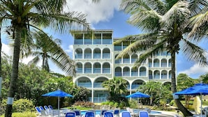 Een hotel met een zwembad, blauwe parasols en ligstoelen.