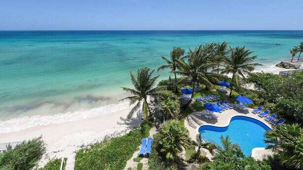 Een resort met een zwembad, strand en palmbomen.