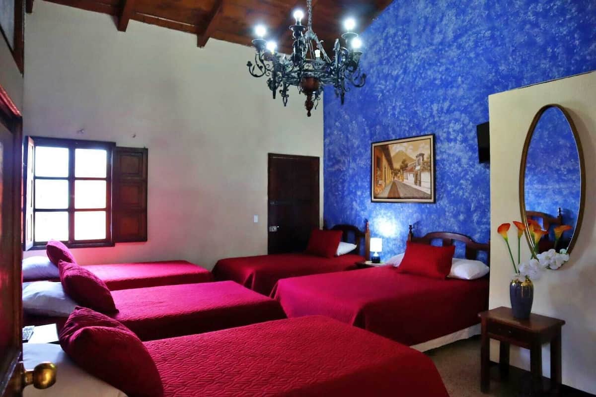 Una habitació amb quatre llits, una làmpada penjolada, un quadre i un mirall.