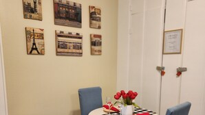 A dining area with a round table, two blue chairs, a small stool, and a checkered tablecloth. - Adorable & Romantic French Corner by Downtown, The Heights & WOMH - Pet Friendly (Houston)