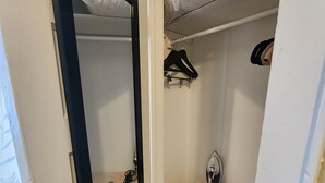 A small, narrow closet with a mirror, a hanging rack, and a vanity with a mirror. - Adorable & Romantic French Corner by Downtown, The Heights & WOMH - Pet Friendly (Houston)