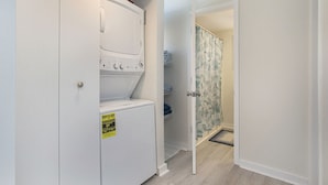 A laundry room with a washer and dryer, a door leading to a bathroom with a shower curtain. - Beautiful 2 bed cottage by Coldwater Lake! (Coldwater)
